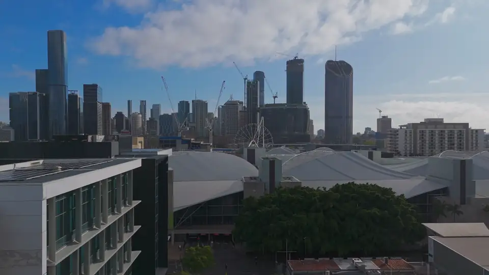 A drone flight along a West End street towards the Brisbane city skyline
