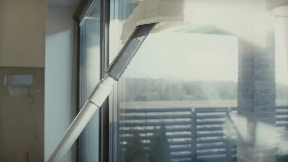 A microfibre pad on a pole wiping a tall window clean